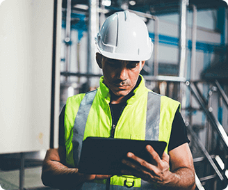 Safety officer using a tablet to track incidents and log corrective actions in an industrial workplace.