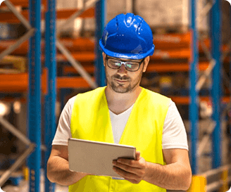 Worker reviewing digital safety permits in a warehouse.