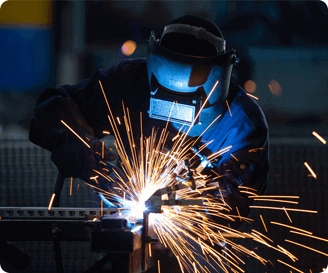 Welder in protective gear creating sparks during metalwork, highlighting fire safety precautions